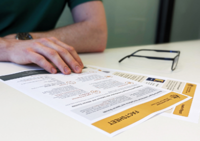 Photo of a person reading fact sheets on a table